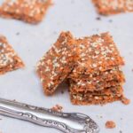 Knapriga frökex med orangefärgad grönsakspulpa på ett fat