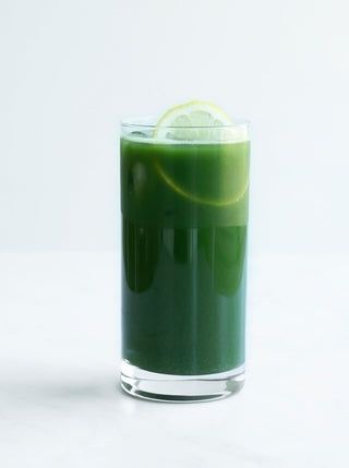 Ett glas med mörkgrön juice och en citronskiva på toppen